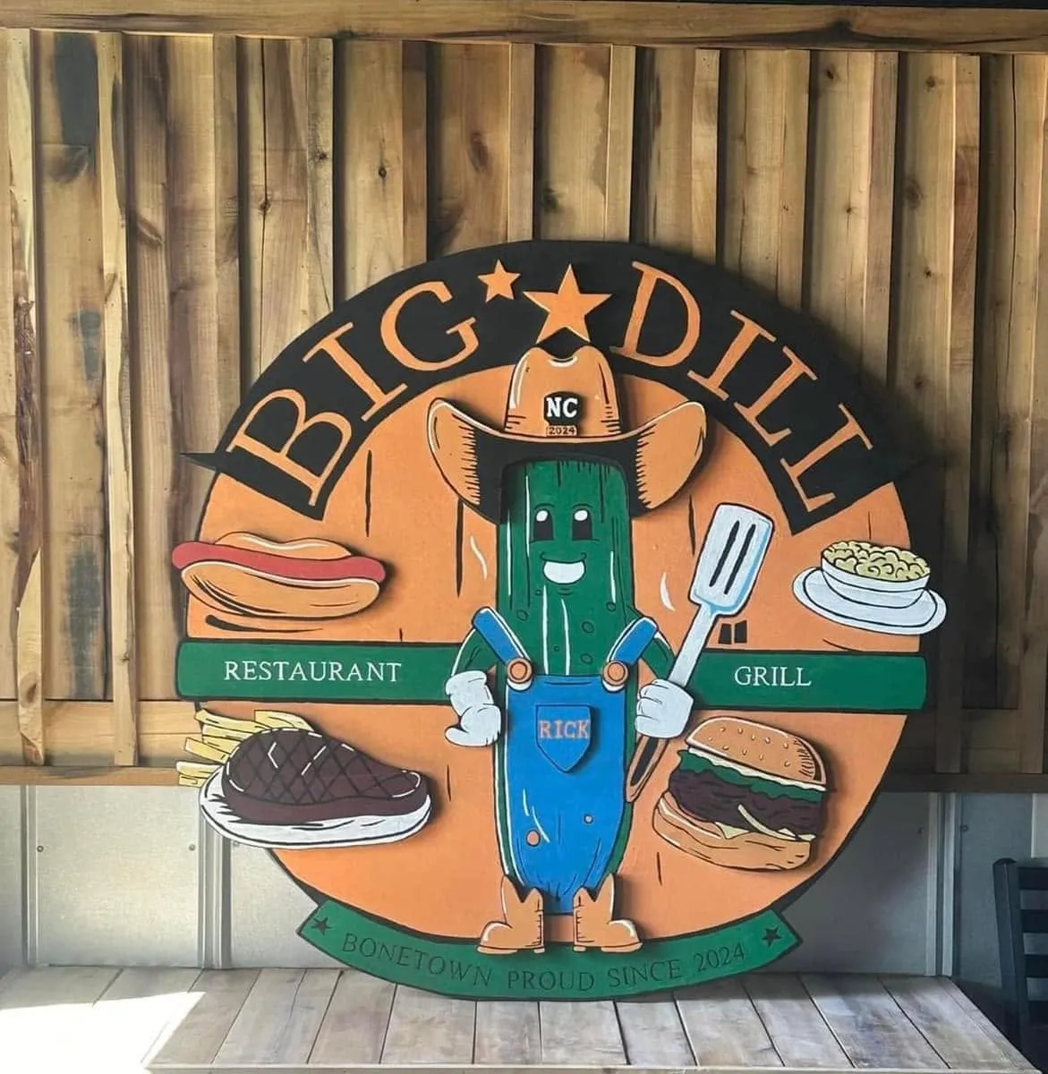 The hand-painted round Big Dill Grill sign with Rick the pickle in a cowboy hat, reading Bonetown Proud Since 2024